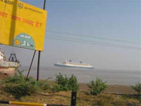 The Blue Lady, formerly the SS Norway, stands in shallow water at the ship breaking yards in Alang, India. A sign in the foreground reminds workers to use safety equipment. © Ken Moritsugu/MCT